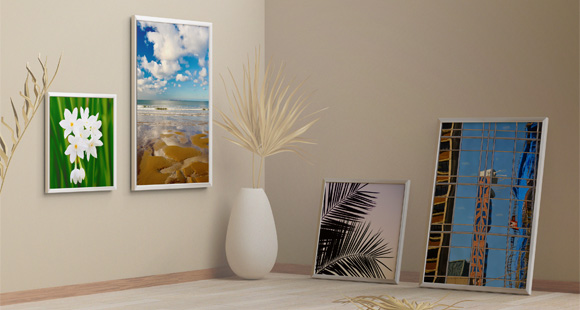 A modern decor scene featuring a white picture frame displaying a vibrant sunset against a colorful sky, surrounded by minimalist vases with dried plant arrangements.